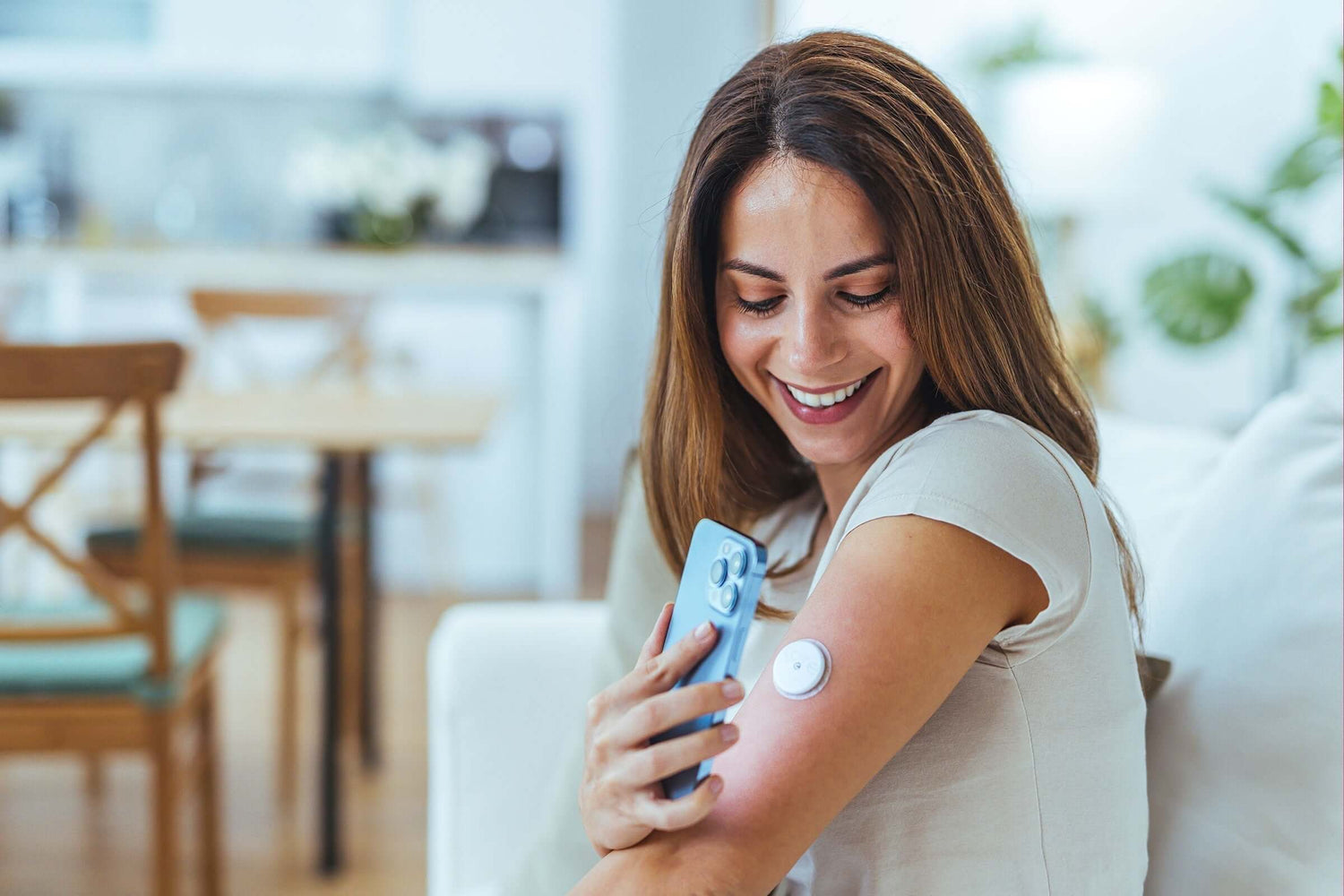 Lächelnde resiliente Frau scannt mit Smartphone ihren Diabetes Glukose Sensor