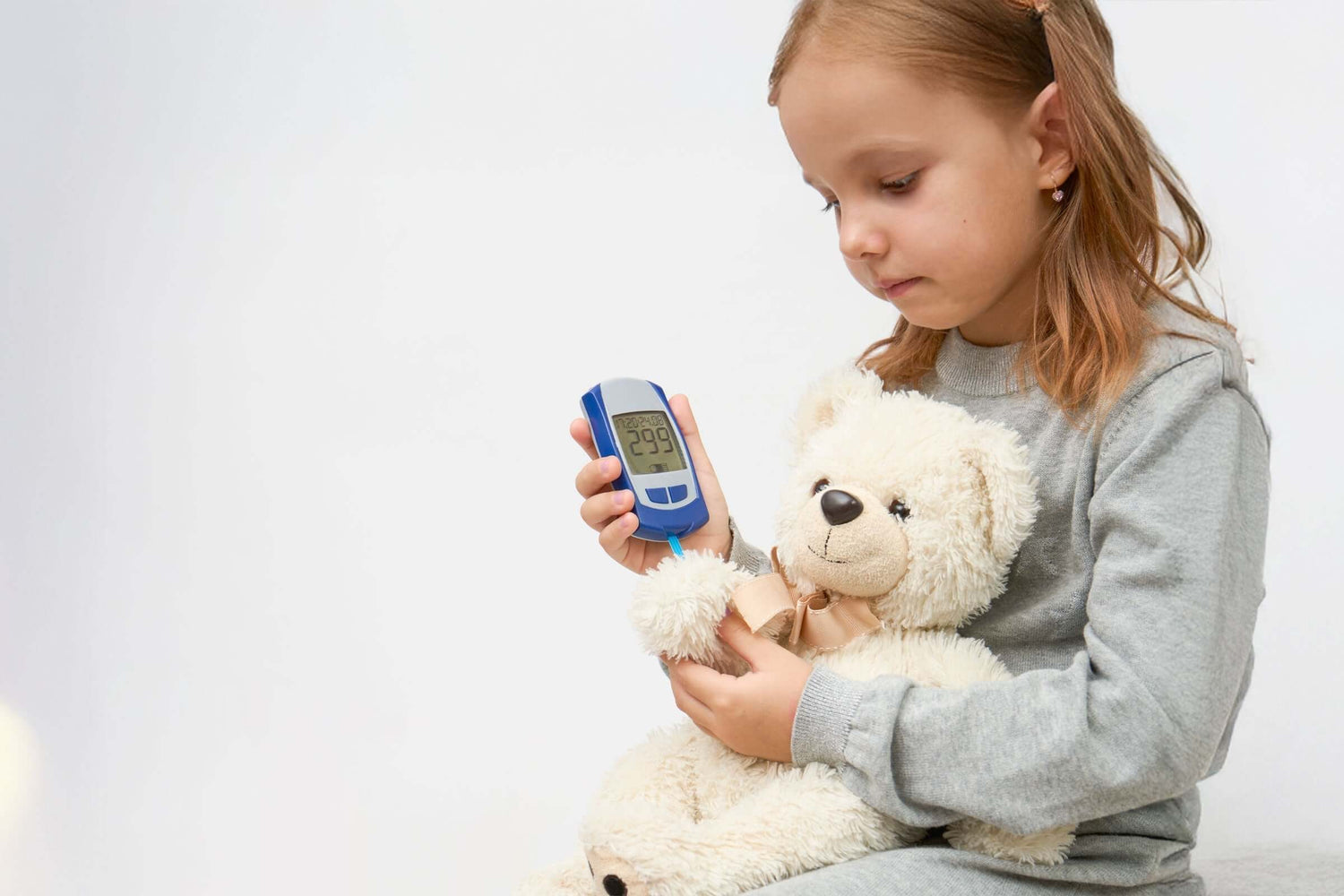 Mädchen mit Teddybär und Glukosemessgerät