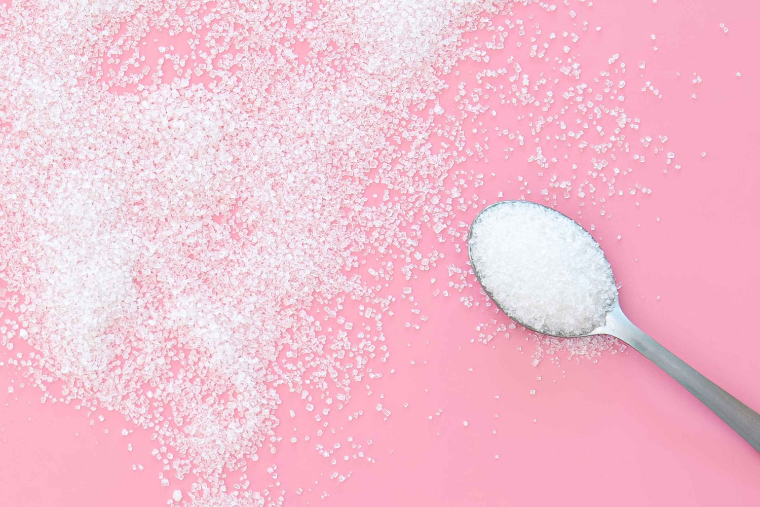 Löffel mit Zucker auf rosa Hintergrund